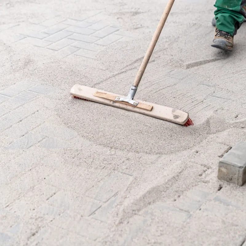 Polymeric sand installation in Hartford County CT — professional sweeping polymeric sand into paver joints on residential patio